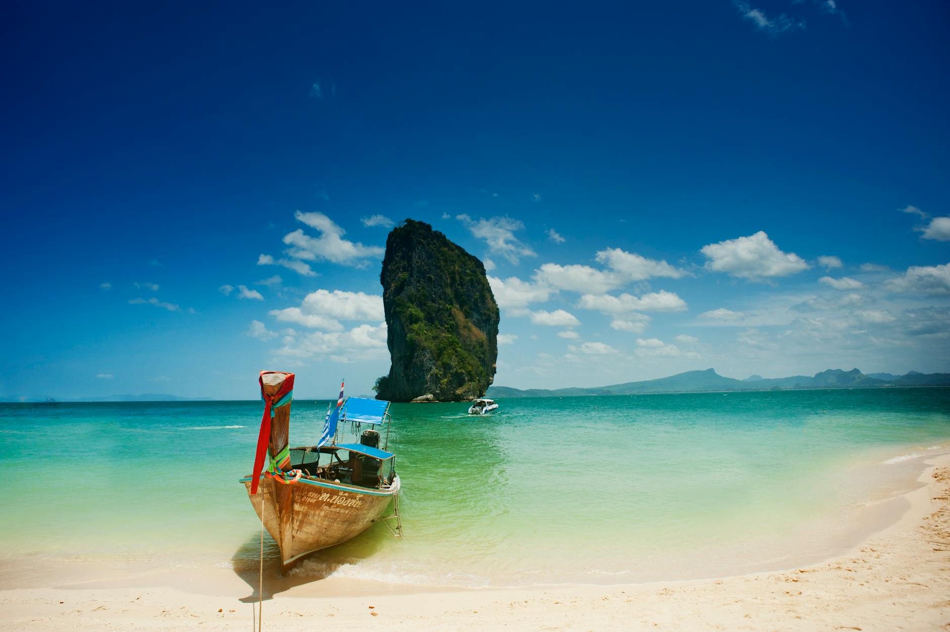 White-sand beach with turquoise waters and palm trees in Phuket, Thailand