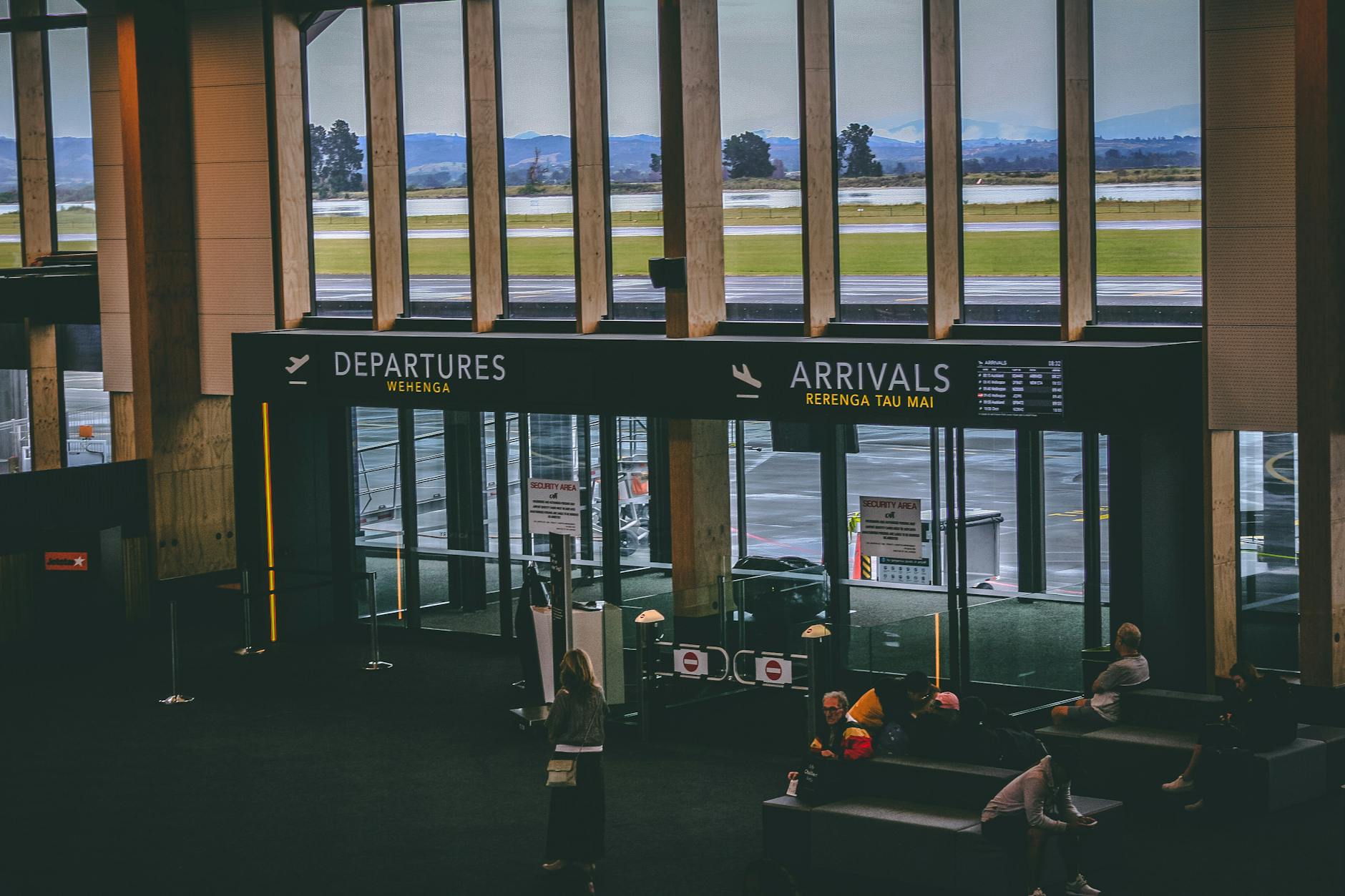 Passengers walking through airport arrivals hall with luggage and signs