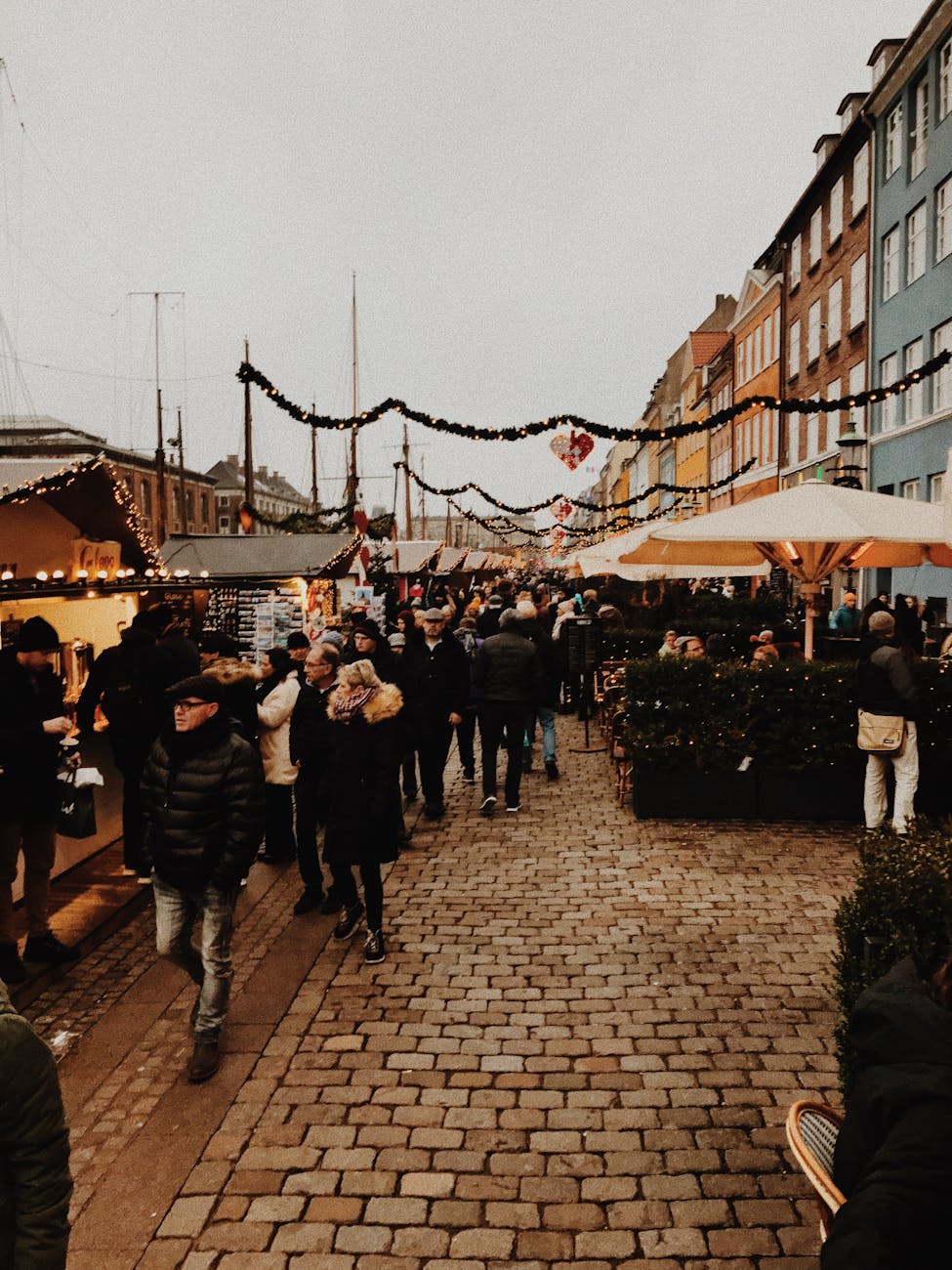 Tourists enjoying Danish holiday markets with mulled wine and treats in Copenhagen, Denmark