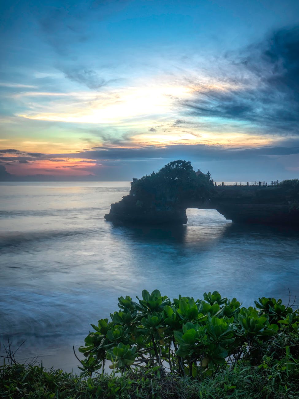 Sunset over a serene beach in Bali with golden skies and calm waves