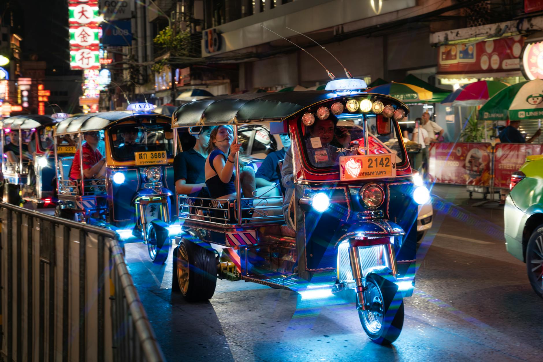 Colorful tuk-tuk driving through neon-lit streets of Bangkok at night
