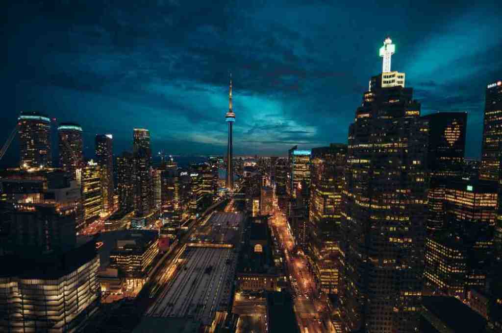 Stunning night view of Toronto skyline, Canada, with illuminated skyscrapers, the CN Tower glowing, and reflections on Lake Ontario, ideal for city tourism and travel photography.
