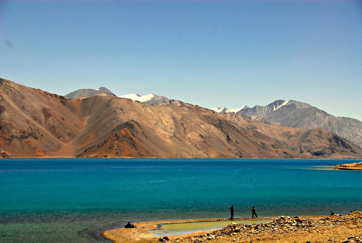 Crystal blue Pangong Lake with mountains in the background, a must-visit spot for travelers planning a Ladakh trip.