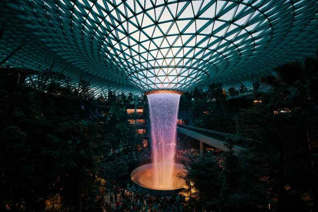 World’s tallest indoor waterfall, HSBC Rain Vortex cascading inside Jewel Changi Airport surrounded by lush forest valley.