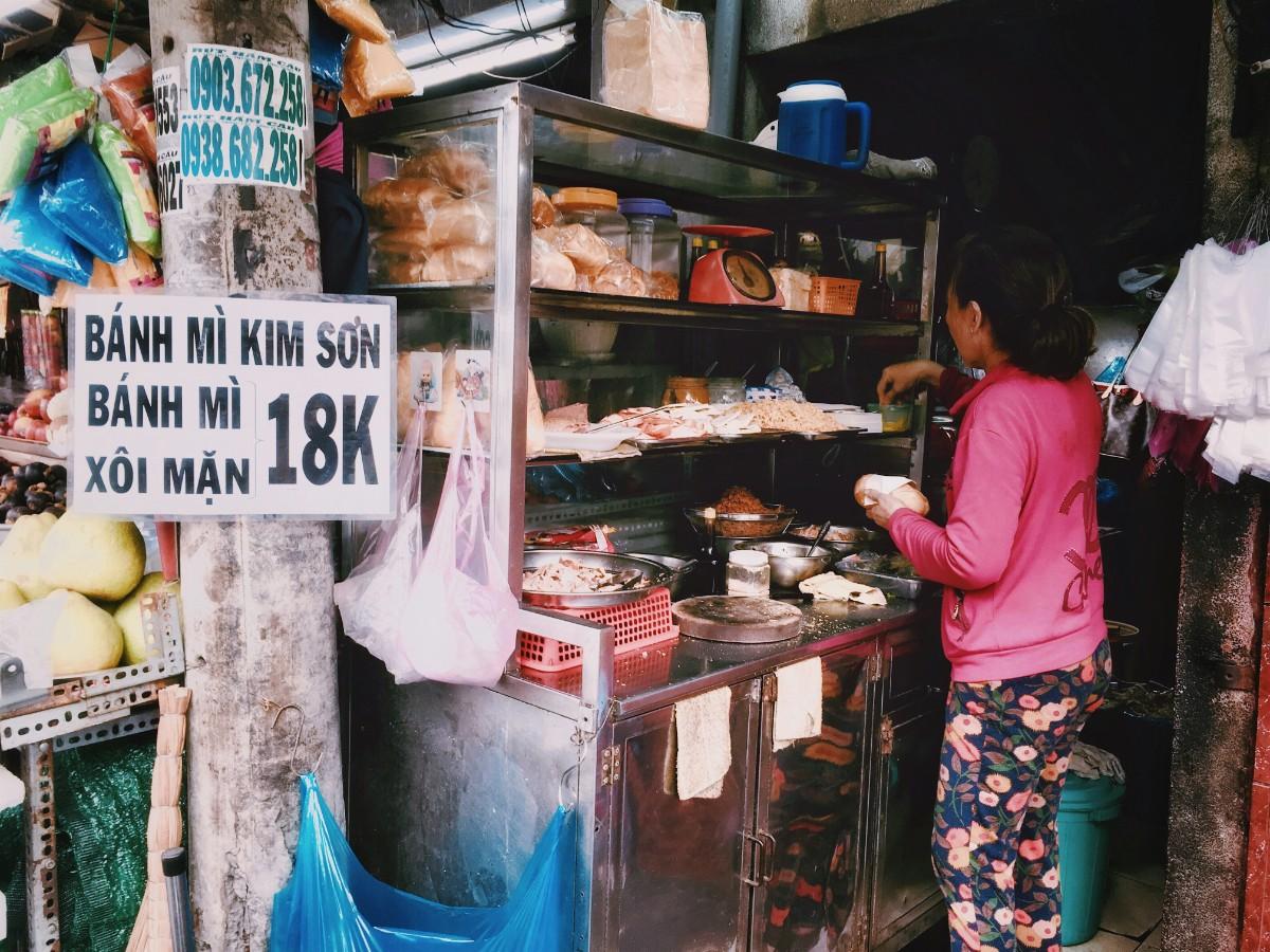 Traditional Vietnamese street-side banh mi restaurant vendor preparing vegetarian banh mi chay with tofu and fresh ingredients
