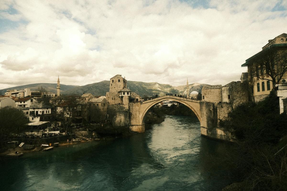 The historic Stari Most stone bridge illuminated at night over the emerald Neretva River in Mostar.